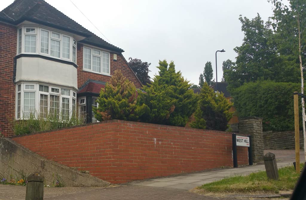 An house with a bay window raised from the pavement and a high brick wall to the front garden.