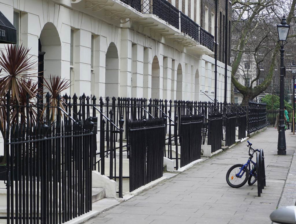 A row of terrace Georgian Houses with steps up to the front door and black railings.