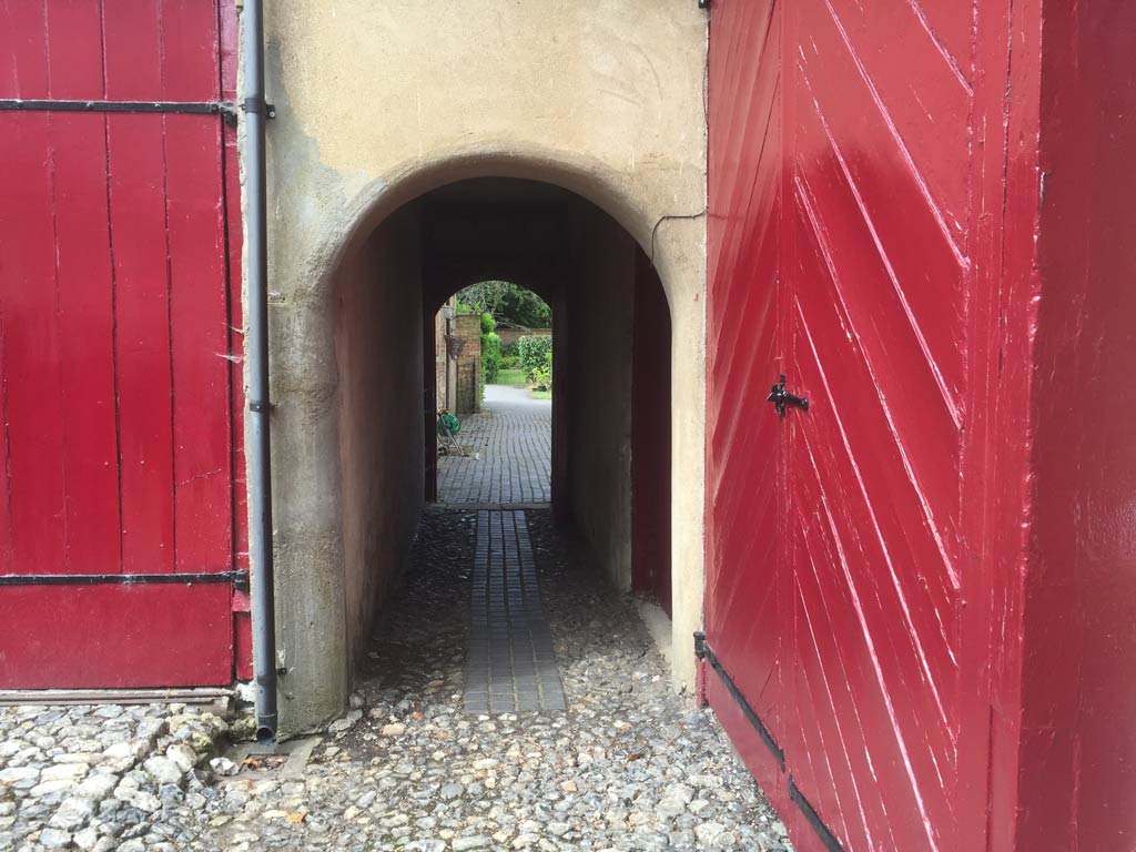 An arched walkway flanked by two very tall bright red doors.