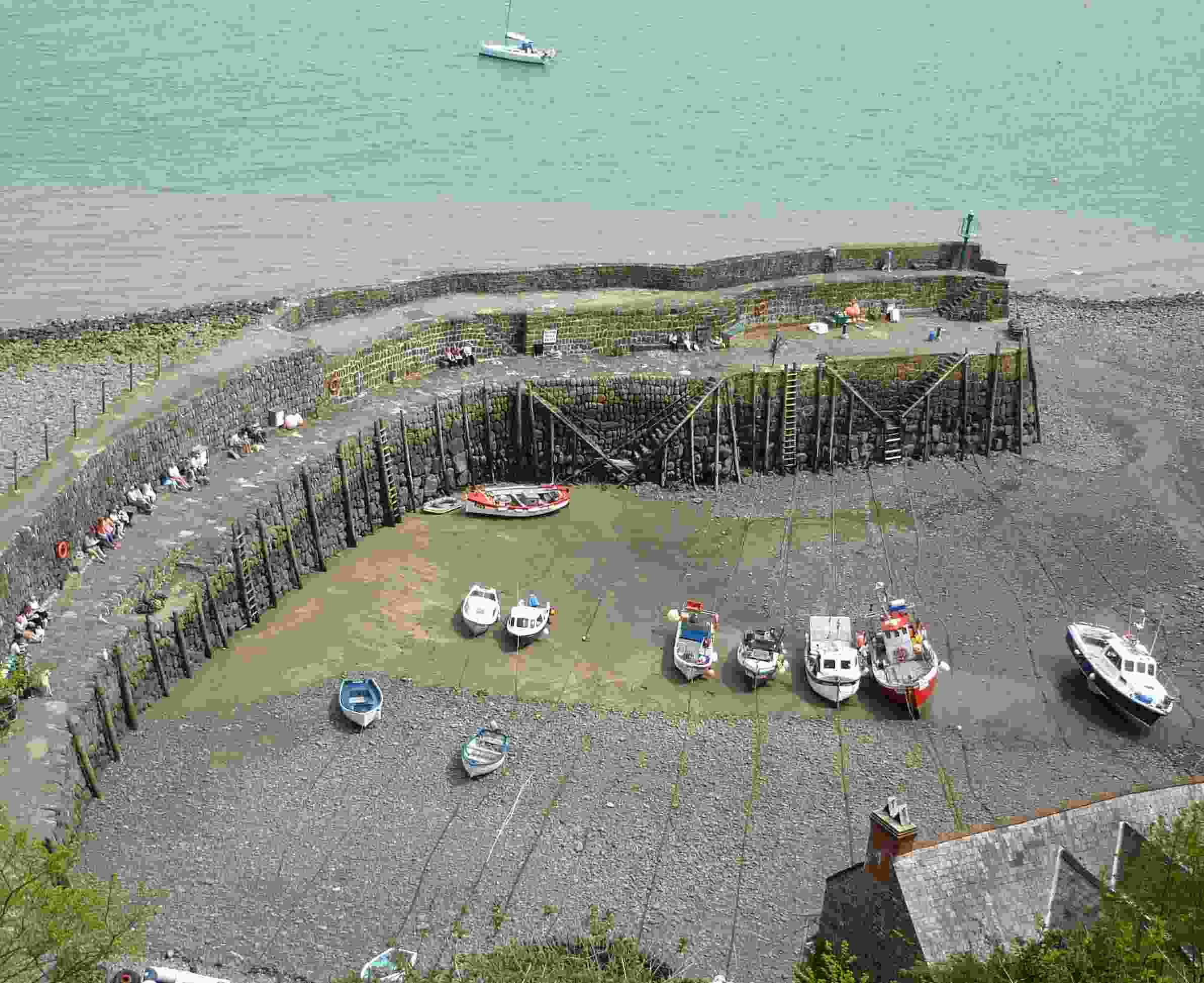 The view down to an arc of an harbour wall and stranded boats as the tide is out.