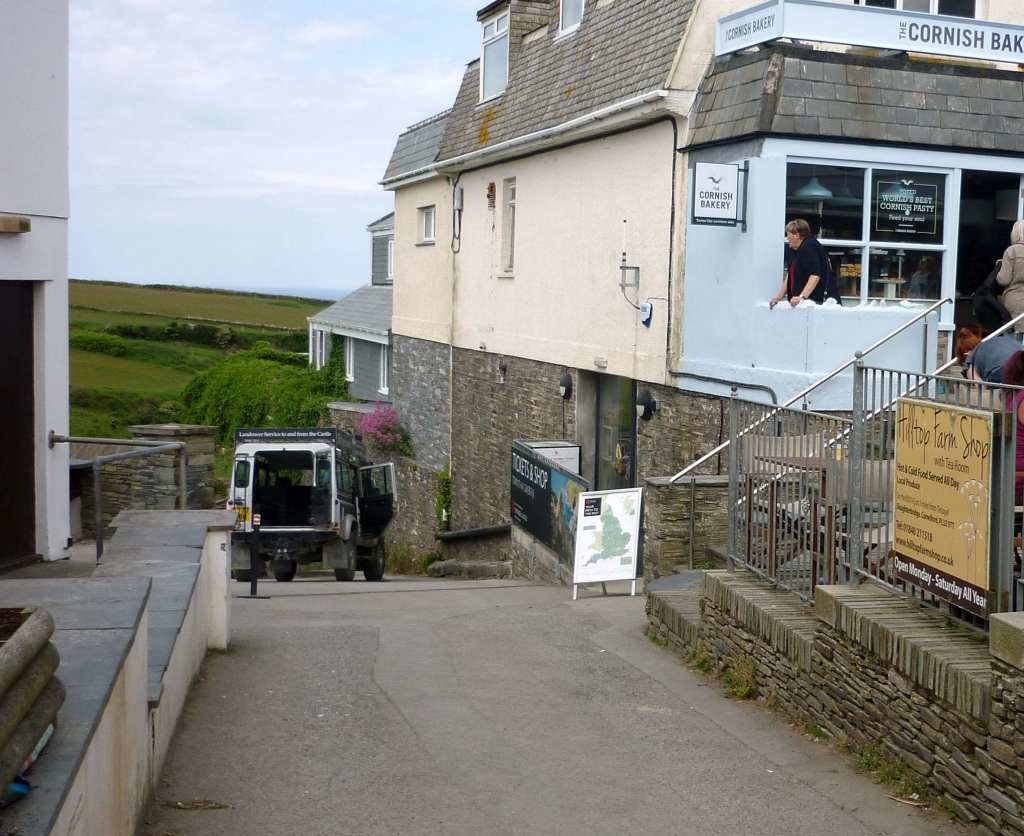 A pasty shop to the right and a steep road down to Tintagel Castle to the left.