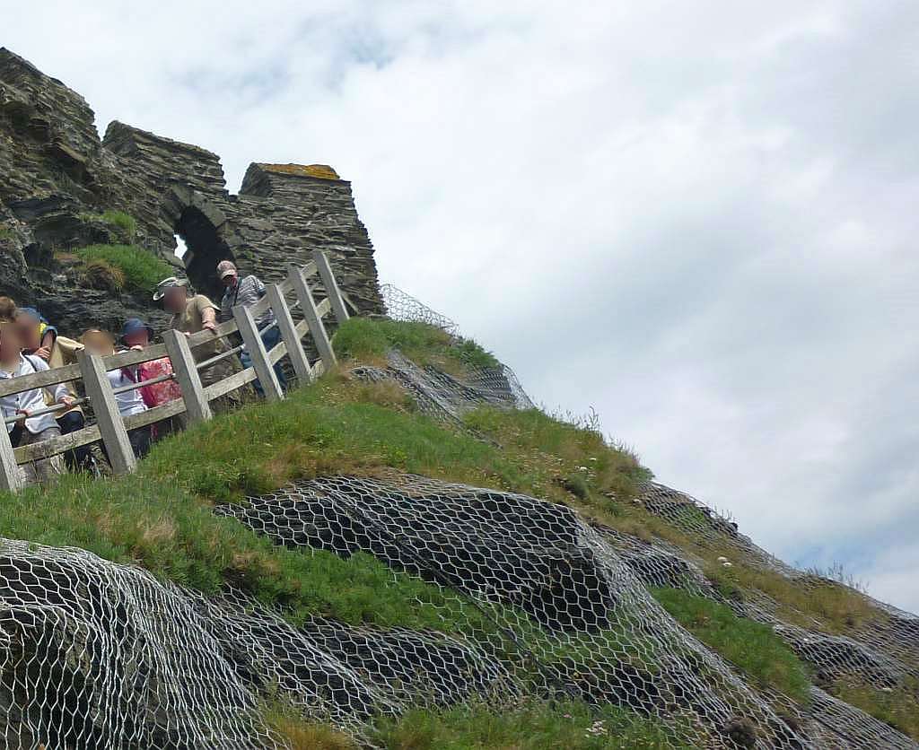 A cliff footpath and the few remaining battlements of Tintagel Castle.