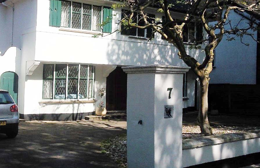 A white house with lead light windows and it's gatepost foreground.