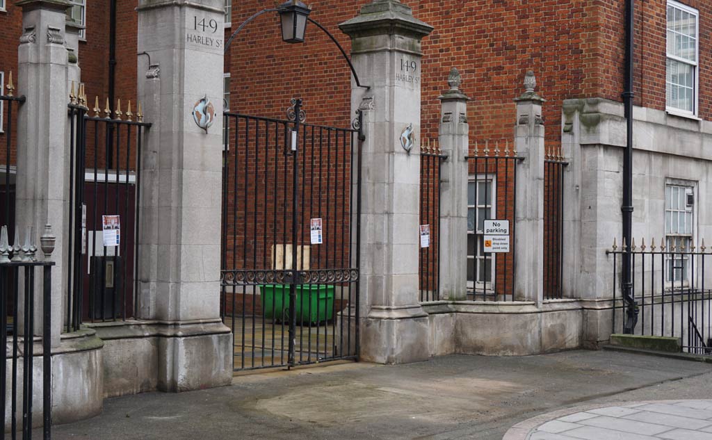 Imposing gatepost with wrought iron gates and railings
