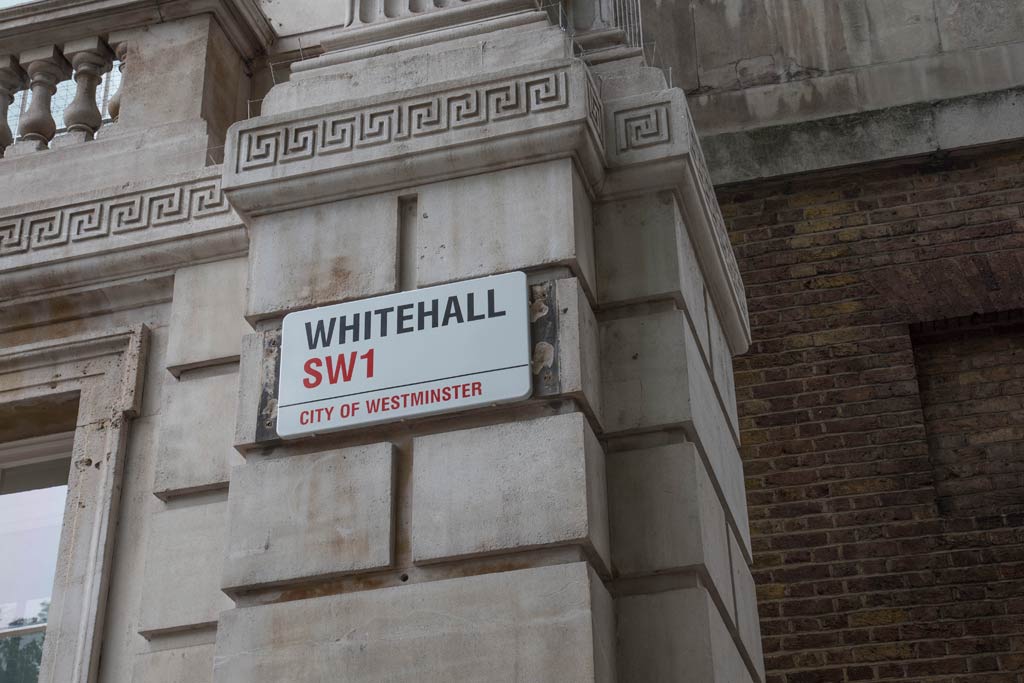 A clos-up of a Whitehall road sign plus a small portion of the stonework, window and balustrade around.