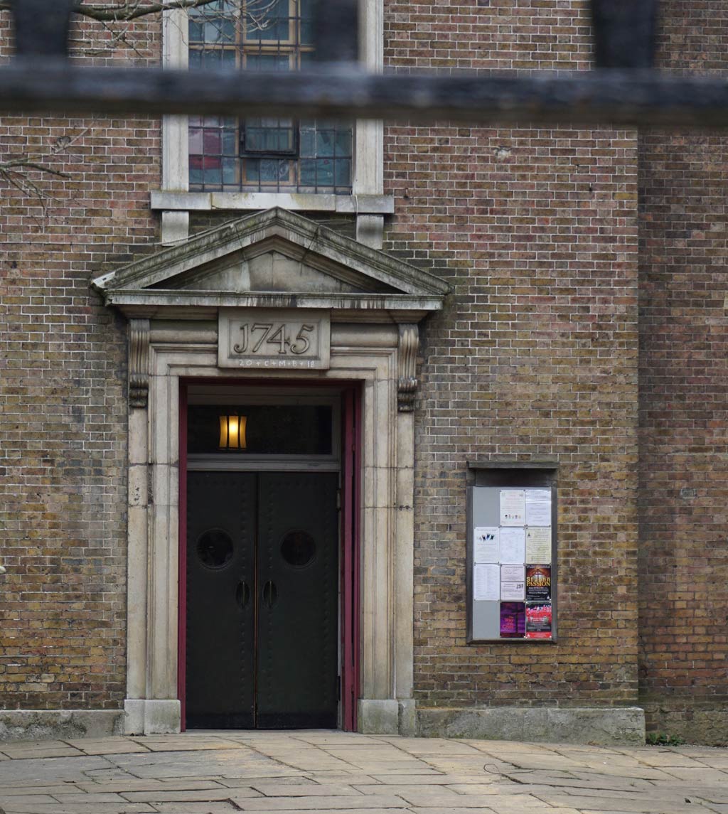 A doorway with a triangular header and a leaded window above.