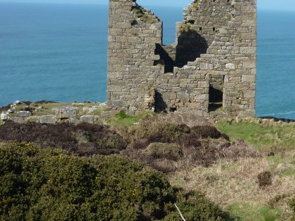 The remains of stone building on a cliff edge with the sea in the background.