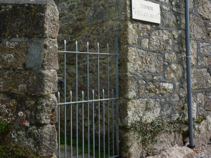 A stone wall building and a wrought iron entrance gate, closed.