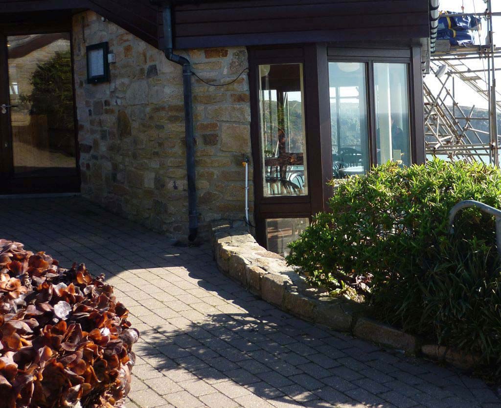 A brick and glass coastal structure through which can be seen the sea and an headland