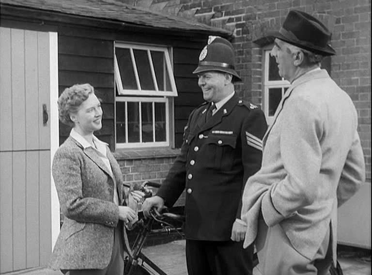 A woman, a police sergeant and a man in the corner of a stable block.