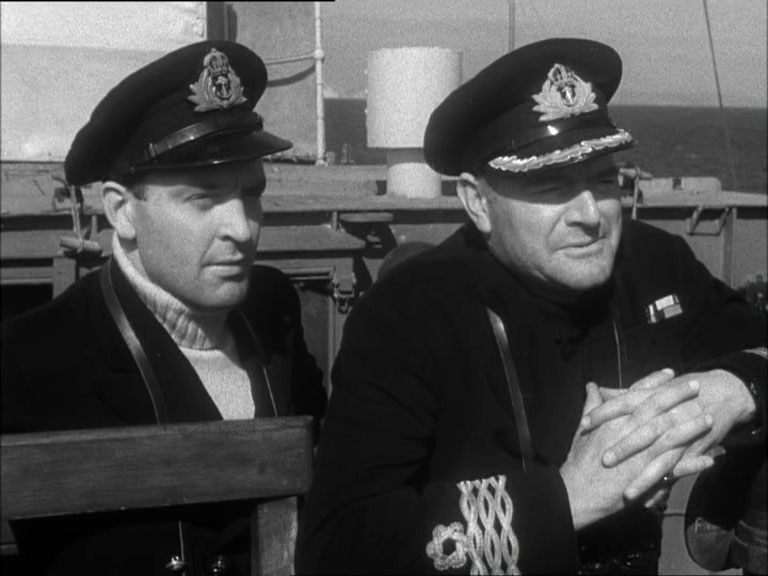 Two men in navel uniform close to camera looking to the right.