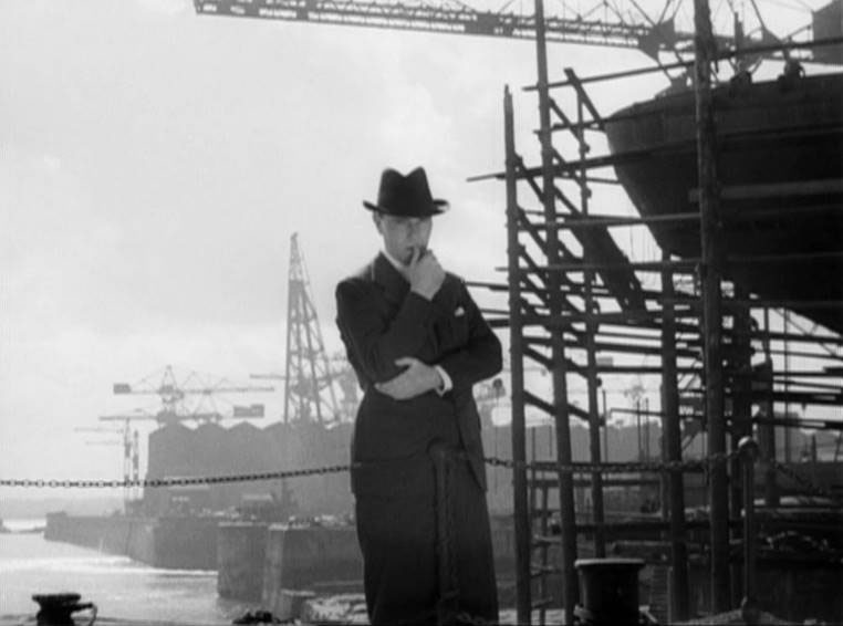 Screen capture from The Silver Fleet (1943) - Jaap van Leyden (Ralph Richardson) oversees work at the shipyard