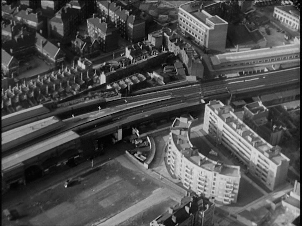 Aerial view of London. Waterloo East Station emerges from the left hand side of the capture and as the line crosses to the opposite side of the capture the telephone exchange on the corner of Hadfields and Meymott Street is prominent above it whilst the apartment blocks Tait House (curved) and Benson House are clearly visible below it. Circa 1956