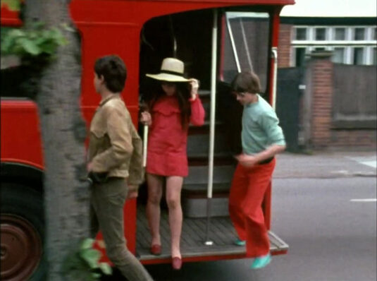 Three teenagers alighting a bus. 64 Coombe Lane West, Kingston upon Thames, Surrey in the background. Circa 1968
